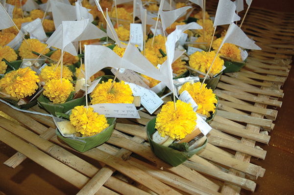 健康で幸せであってほしい家族や恋人の名前を書き、黄色い花やお札と一緒に捧げるPhoto © Mirei Sato